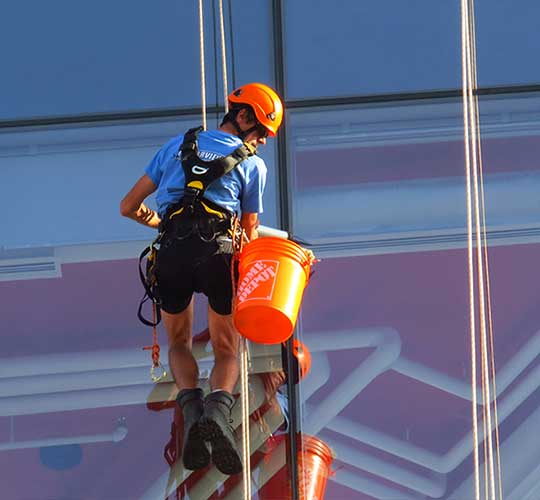 man in harness cleaning windows